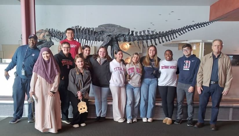 Group photo of several individuals in front of dinosaur bones