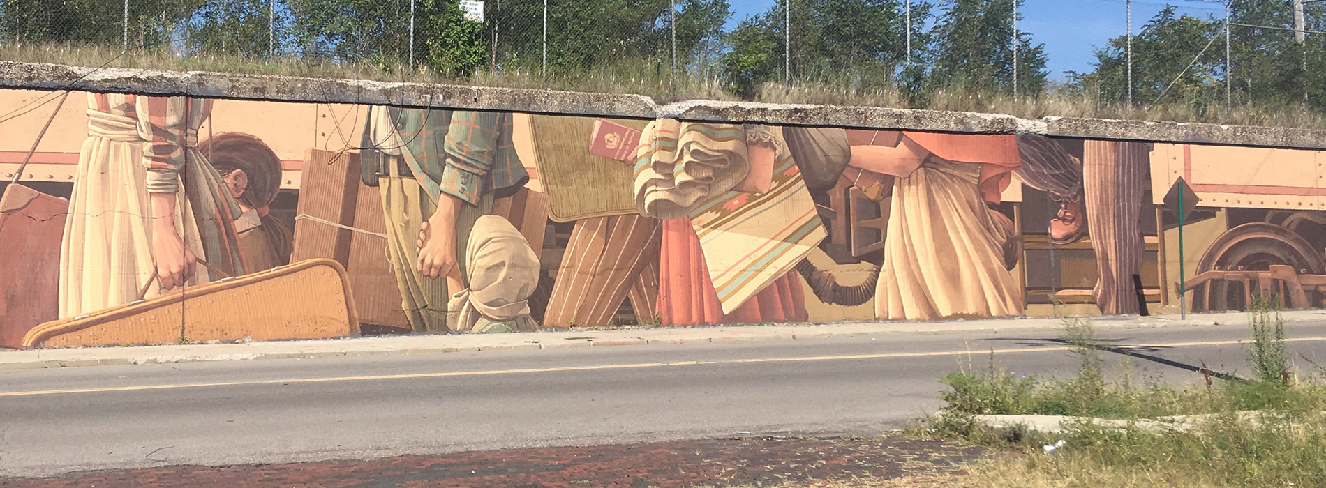 A mural on a long wall depicts passengers getting on a train, in Detroit.