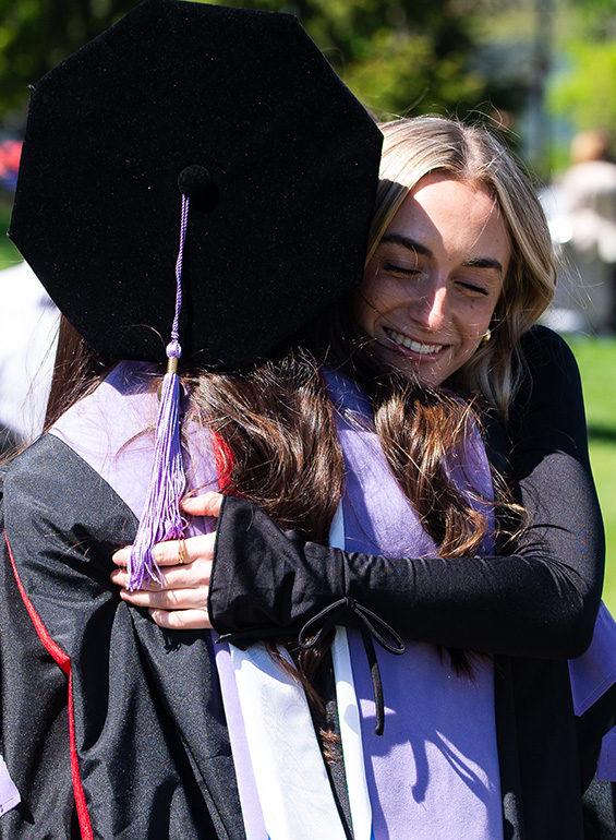 A graduate hugs a woman at commencement.
