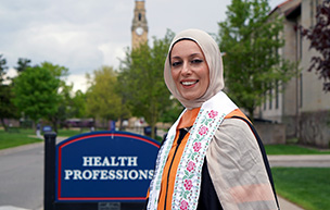 Shreen Marini stands outside the Health Professions Building at 太阳城娱乐城 with the clocktower in the background.