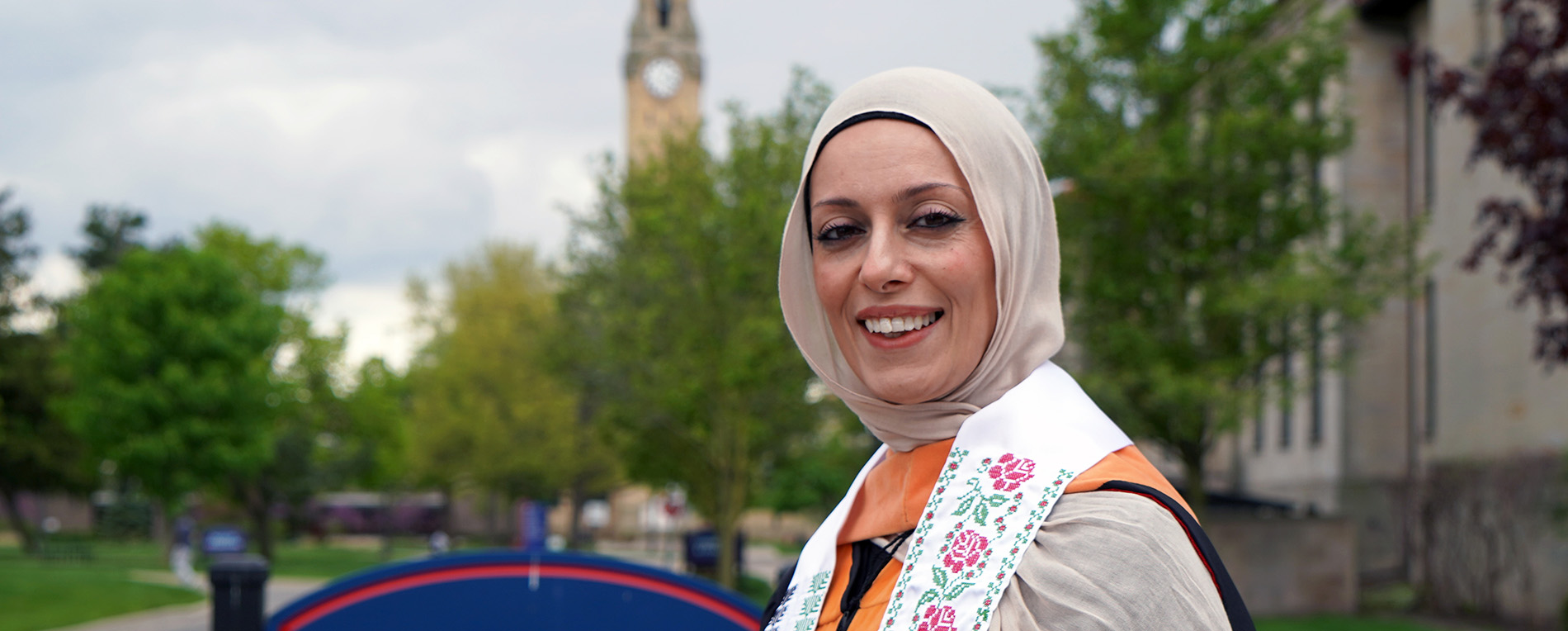 Shreen Marini stands outside the Health Professions Building at 太阳城娱乐城 with the clocktower in the background.
