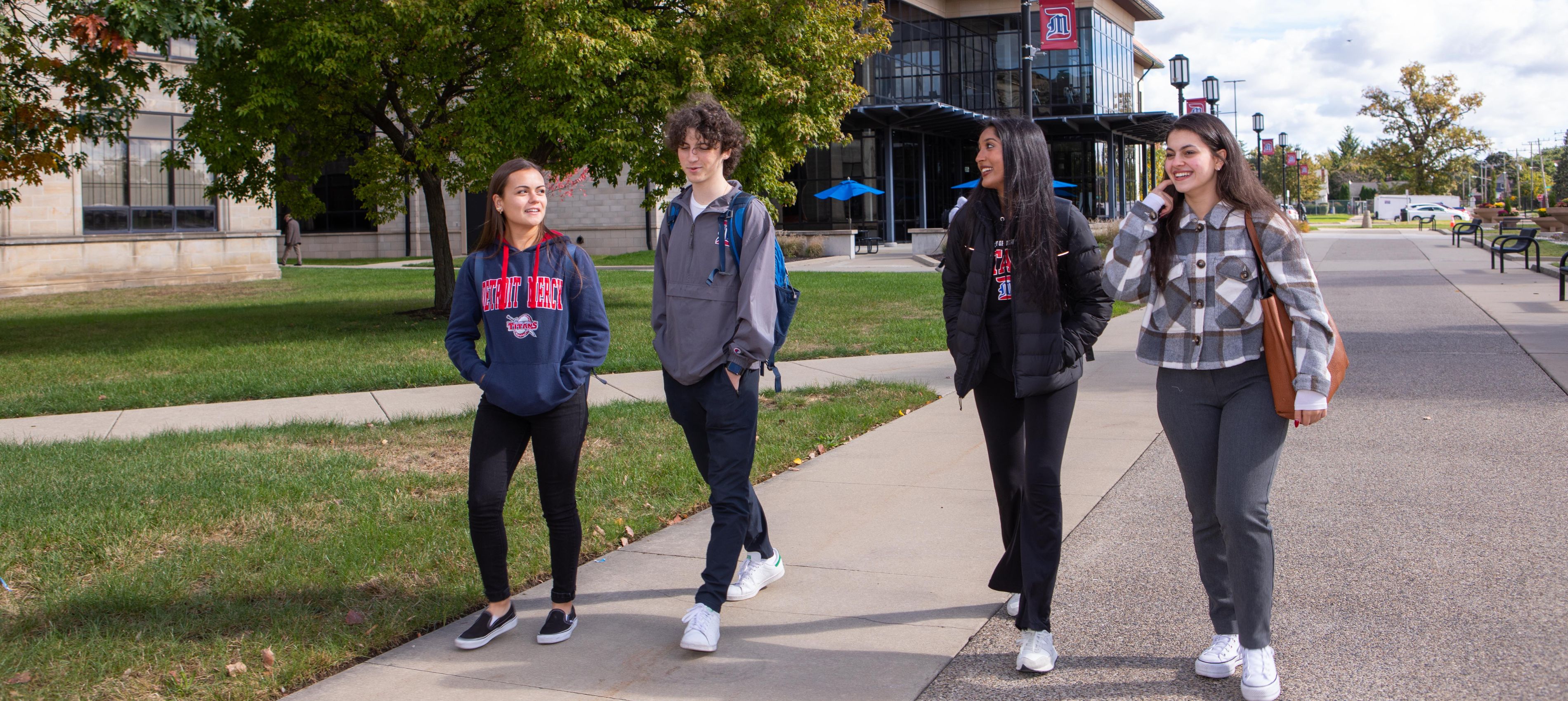 Four 太阳城娱乐 students walk on campus during a spring day.