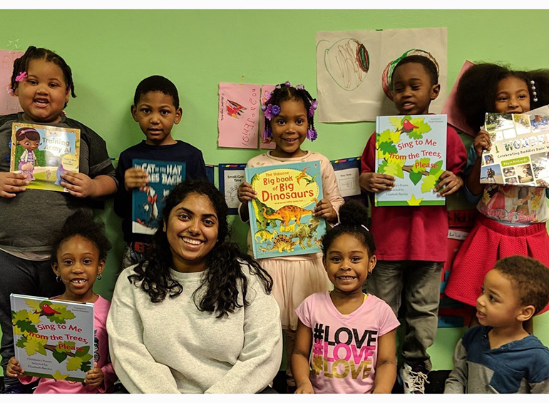 several children and teacher holding books