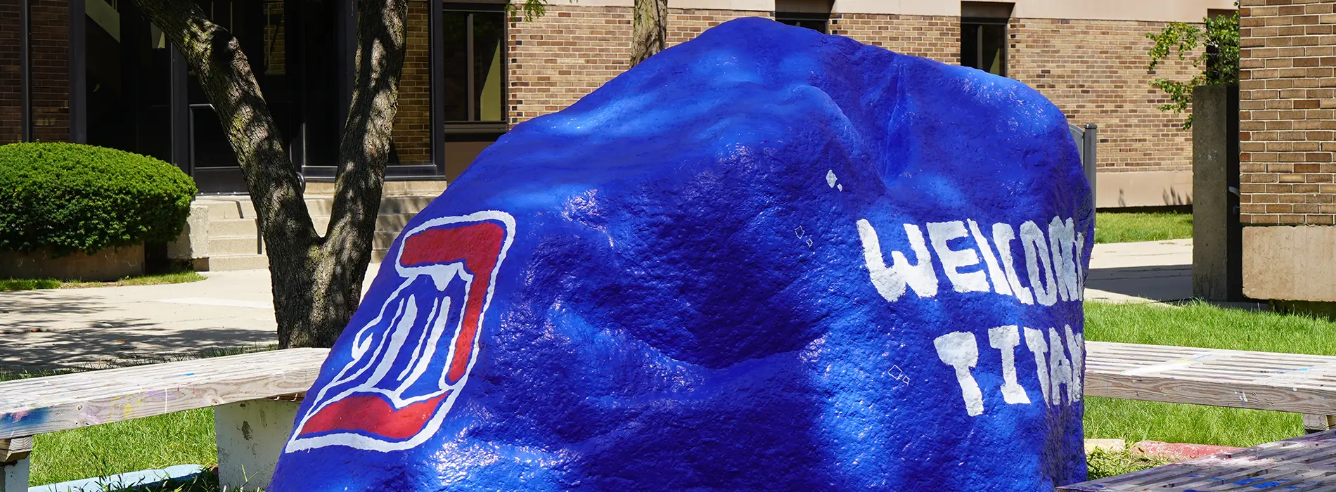 Students standing in front of the rock.